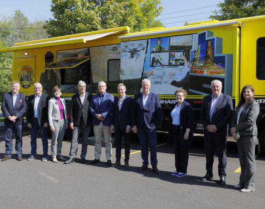A group of people and yellow truck behind them