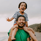 A child sitting on his father's sholder and laughing